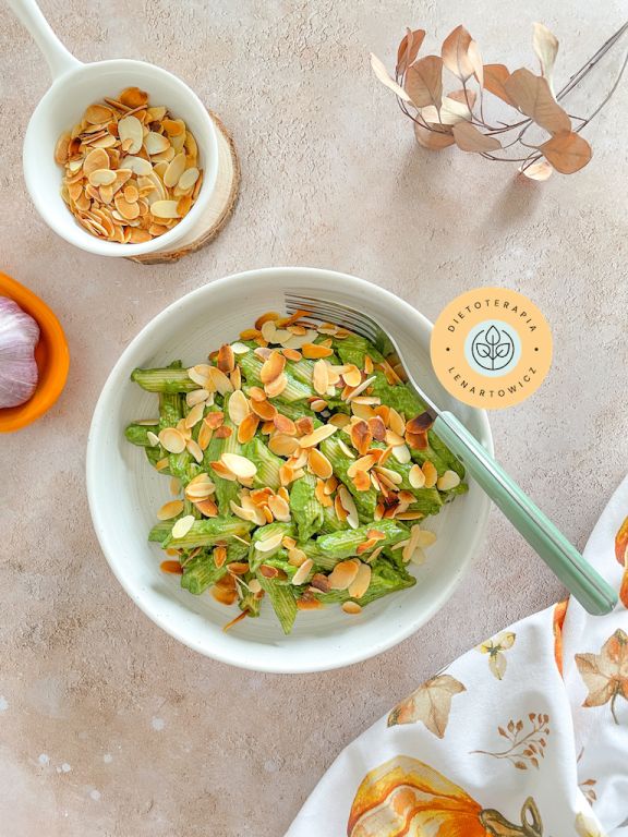 Zdjęcie dania o niskim indeksie glikemicznym, makaron penne wymieszany z sosem szpinakowym i posypany migdałami. Przepis z gotowej diety dietetyka klinicznego Małgorzaty Lenartowicz, edycja jesienna, wersja 3.