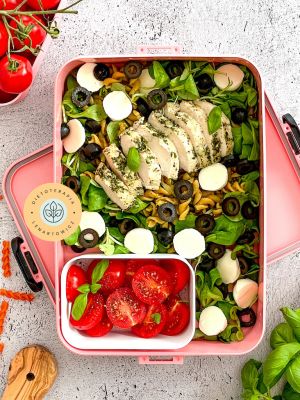 Dietetyczny lunch w pudełku, sałatka z mozzarellą, roszponką, oliwkami, kurczakiem, pomidorkami i dodatkami.