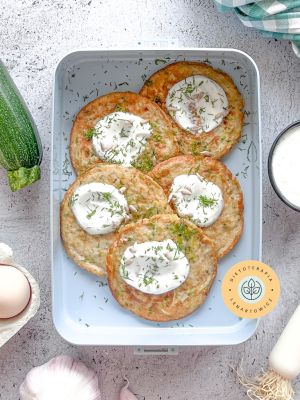 Placki z cukinii i pora, z dodatkiem styru z koperkiem, zapakowane do pudełka na wynos. Zdrowe śniadanie do zabrania do pracy.